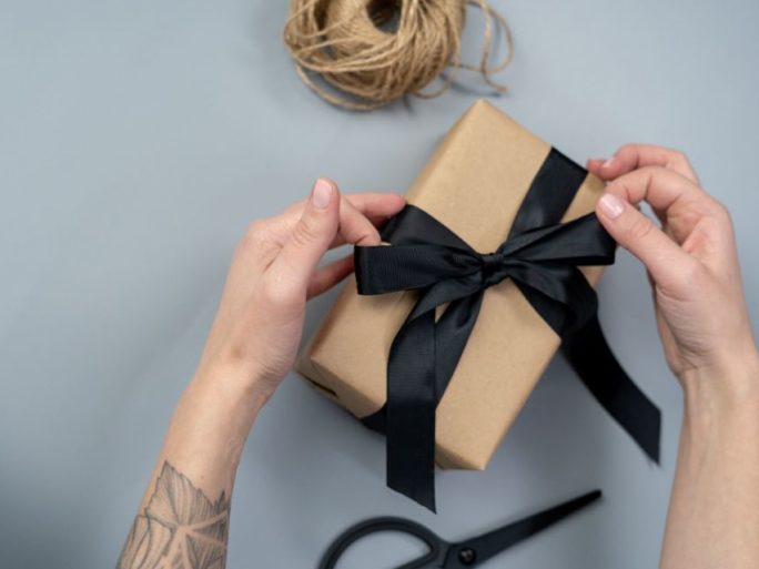 hands tying a bow around a box