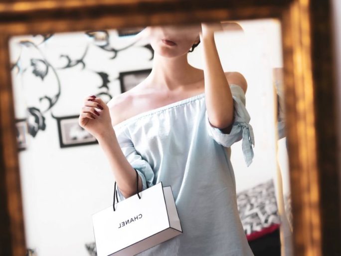 woman in mirror holding chanel carrier bag